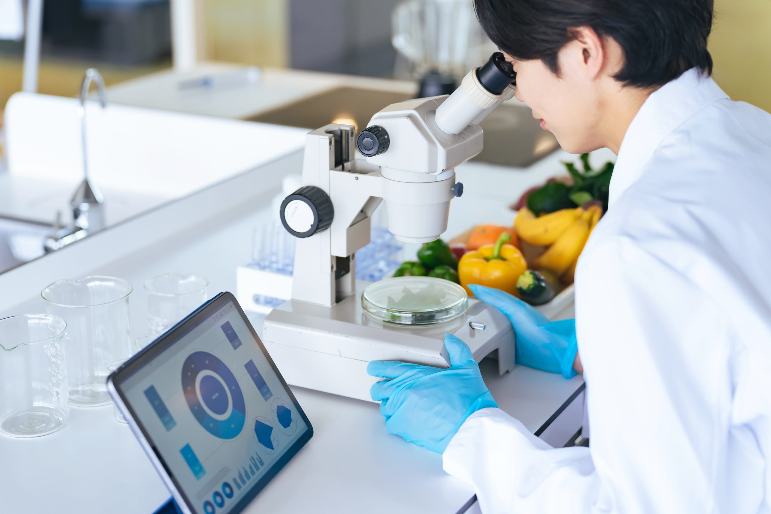顕微鏡で野菜の成分を観察する若い研究者　管理栄養士